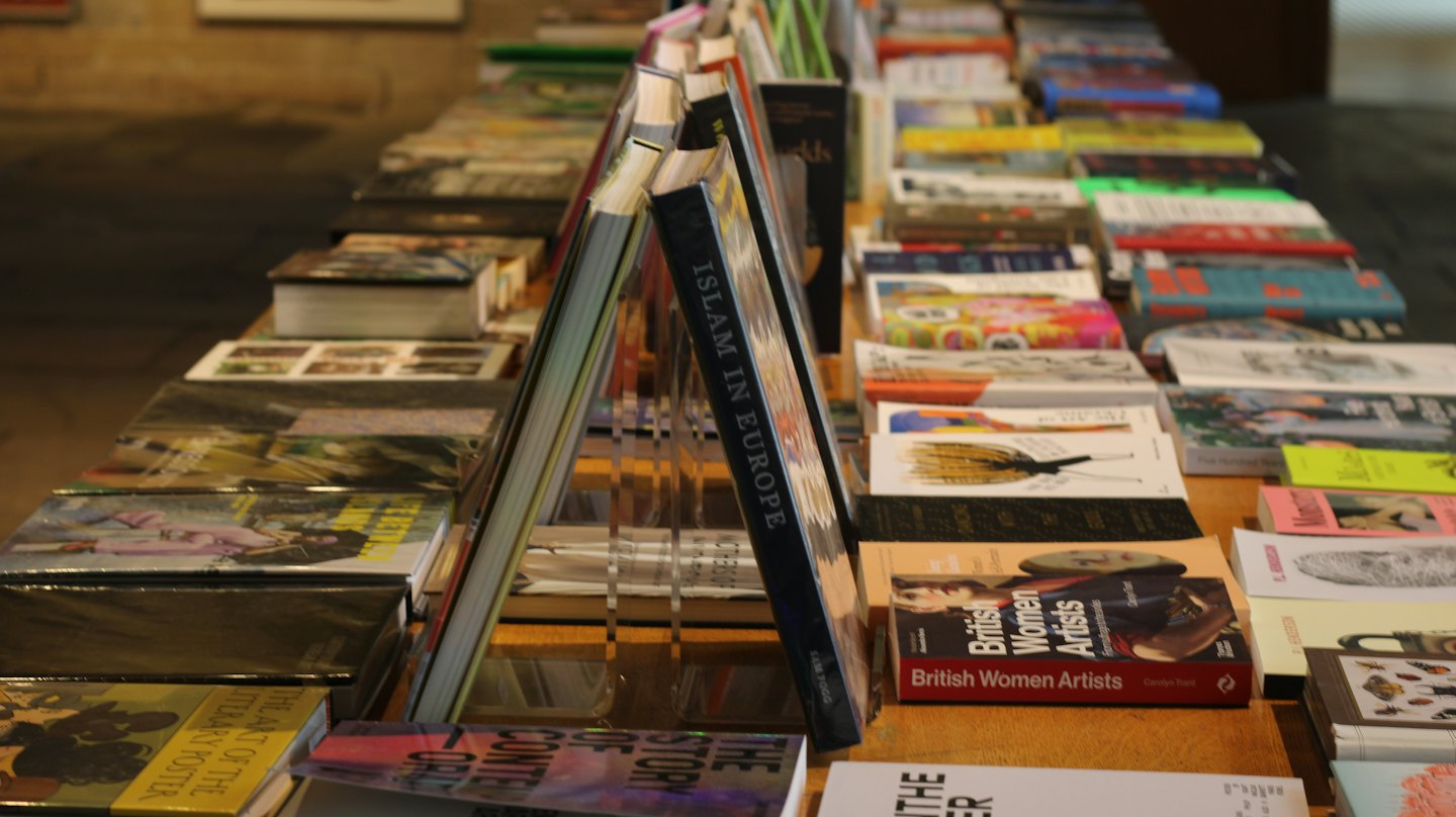 Lungo tavolo pieno di tanti libri e riviste colorati.
